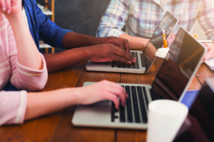 Programmers working in software developing company Unrecognizable team of young programmers working in software developing company, typing on laptops, testing new games or apps, copy space