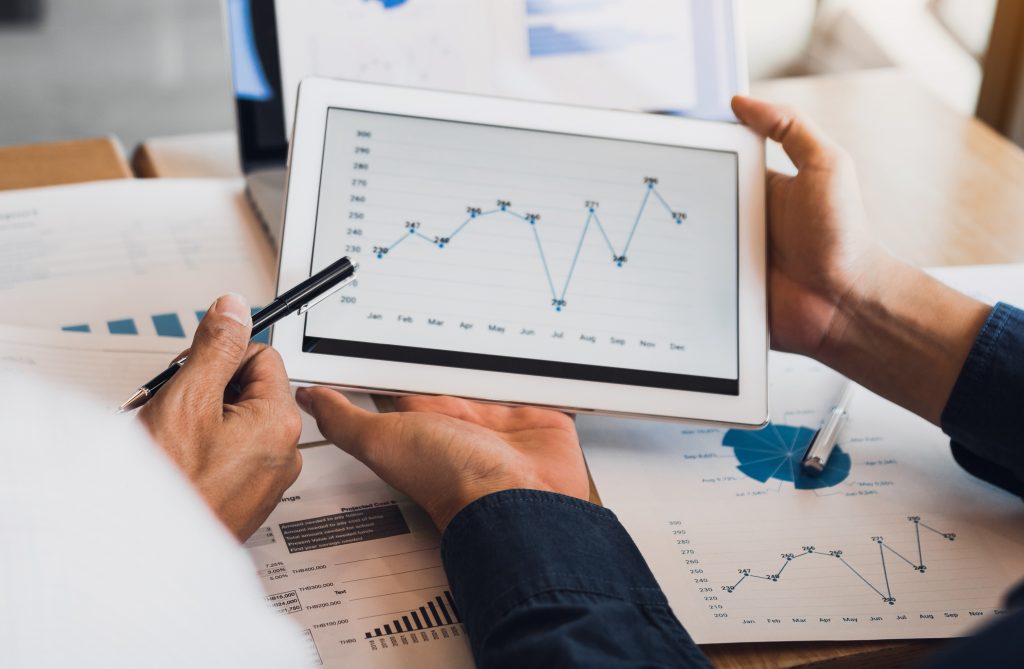 Business partnership coworkers using a tablet to chart company financial statements report and profits work progress and planning in office room. Business partnership coworkers using a tablet to chart company financial statements report and profits work progress and planning in office room.